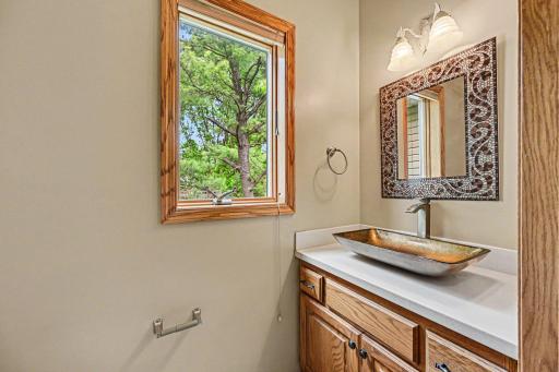 The main level features a half-bath just off the back entryway. It features a storage vanity with a vessel sink, a window and ceramic tile floors. The hallway includes access to garage, a coat closet & a double linen closet for storage.