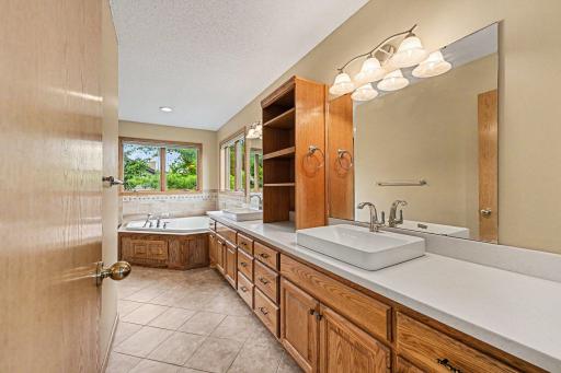 Relax in your own private oasis. This spa-like primary bath showcases an extra-large vanity with twin sinks and excellent storage, completely illuminated by natural light pouring through large corner windows.