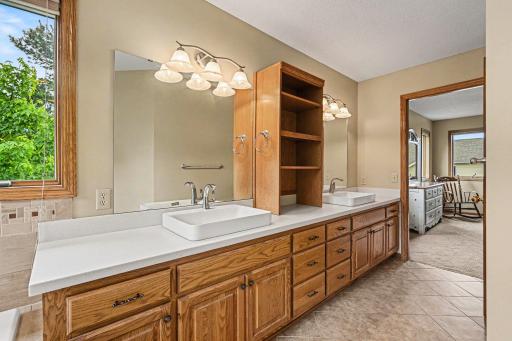 Another view of the massive primary bathroom vanity! This angle highlights the double sinks, endless storage drawers, and the bright combination of vanity lights, modern canned lighting, and natural light from the corner windows.
