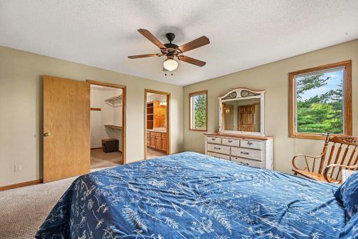 This view of the primary bedroom perfectly highlights the spacious walk-in closet and private full bathroom. Wake up to beautiful, serene views, as this master suite overlooks the large and private backyard!
