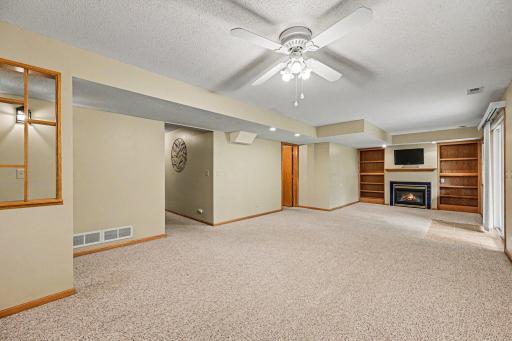 Cozy up downstairs! This view highlights the family room's built-in bookcases and gas fireplace. Hidden from sight but close by, this lower level also includes a massive dedicated storage room and handy under-stair storage.