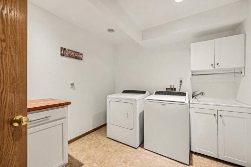 The finished laundry room features custom built-in cabinets with a counter (2024), Whirlpool washer/dryer, and a deep sink. It also accesses the utility room, housing a York furnace, 50-gallon water heater, and a Culligan rented softener.