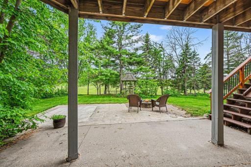 The walkout steps onto a concrete patio with a built-in firepit and hidden under-stair storage. Enjoy your private gazebo and serene, open views, as the yard directly overlooks Golfview Park East & soccer fields for ultimate privacy!