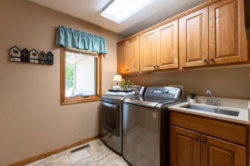 Main level laundry with storage cabinets and utility sink. Perfection!