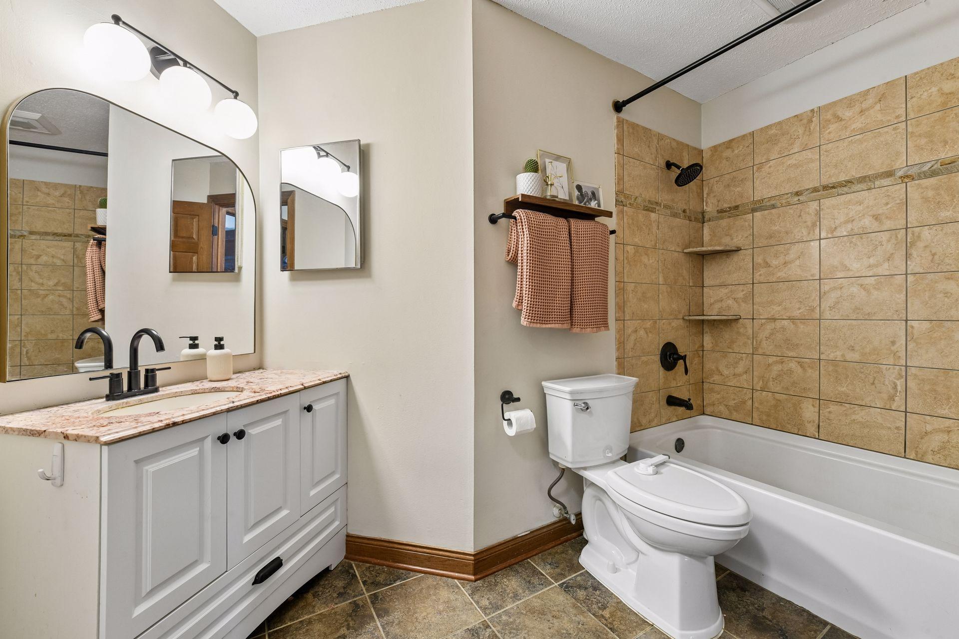The main level bathroom has been updated with a furniture style vanity, tiled flooring, a tiled bathtub surround and designer fixtures.