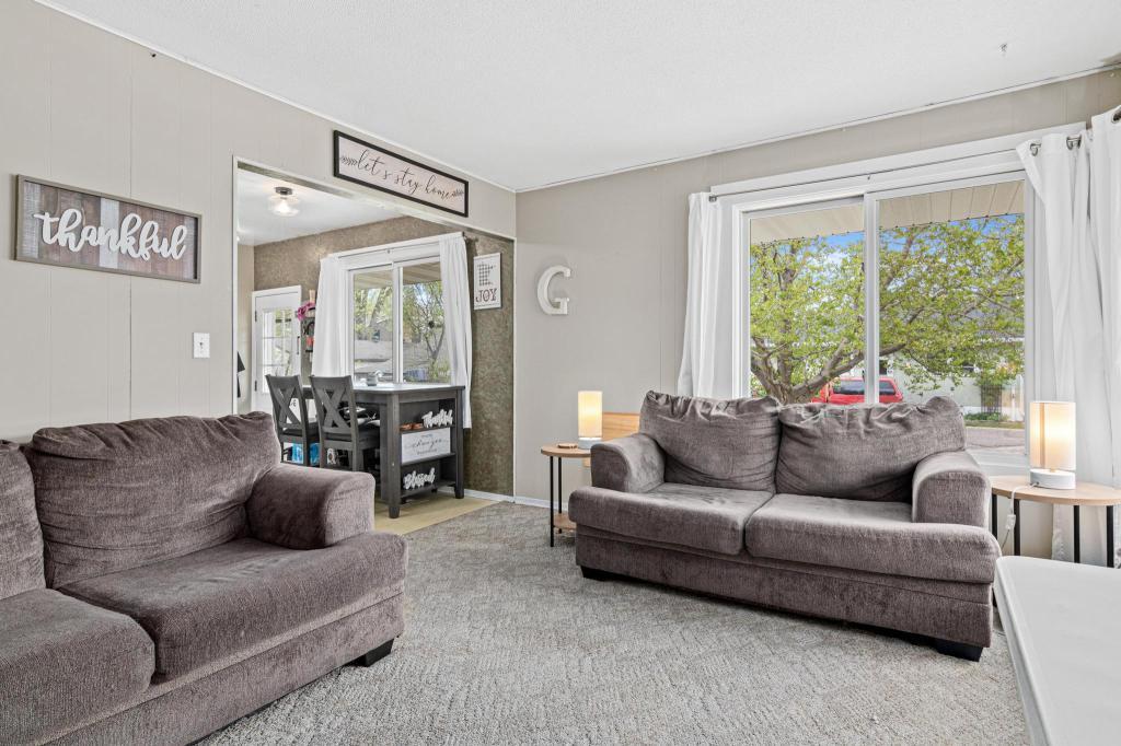 Spacious, inviting living room on the other side of the duplex. Hardwood floors under the carpet - add instant appeal by removing the carpet and exposing the floors. Newer windows throughout the duplex.