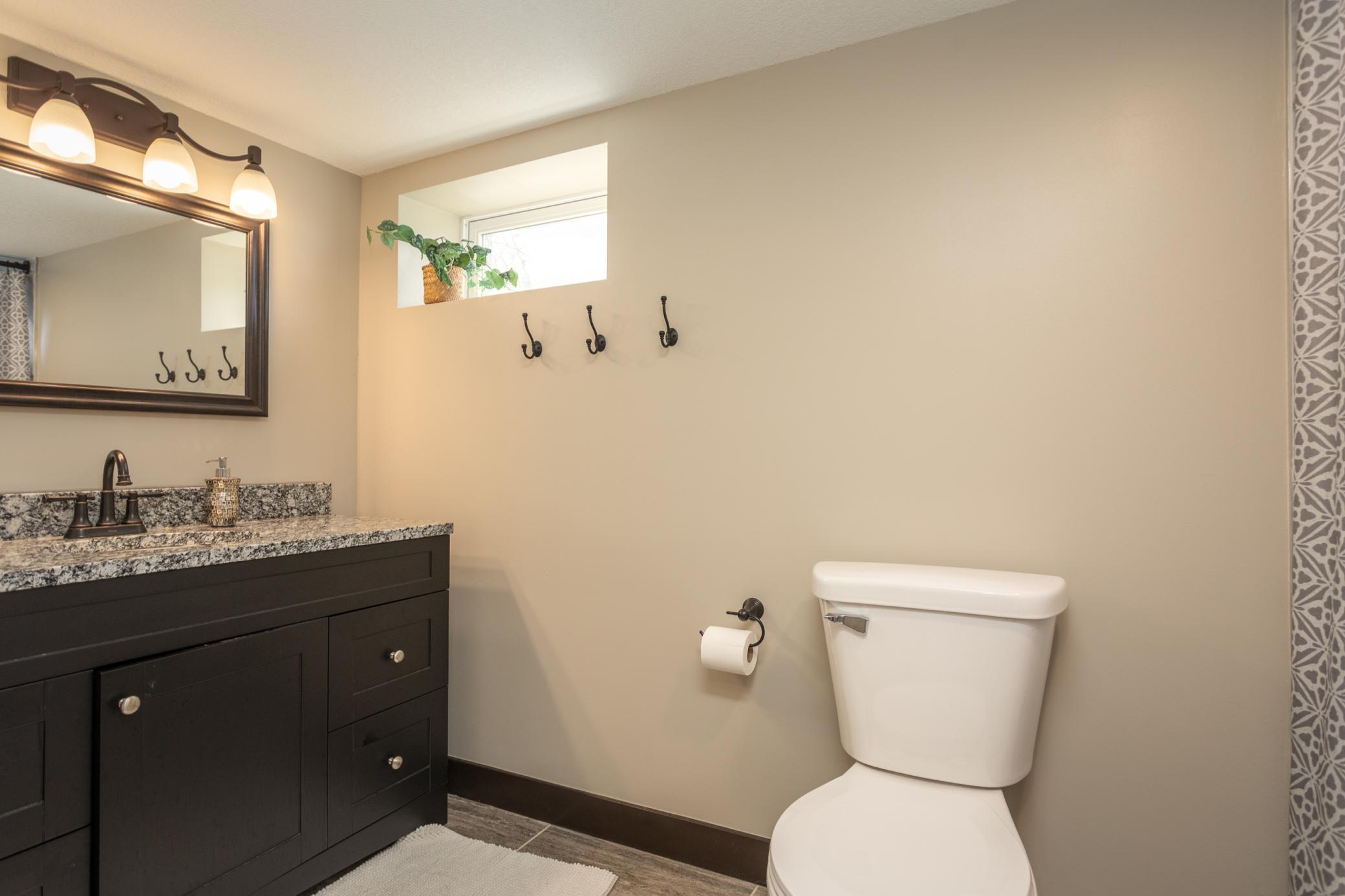 Full downstairs bathroom with sleek finishes and convenient hooks.