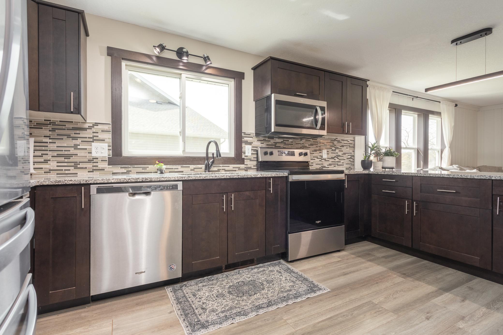 Modern kitchen featuring dark cabinetry, stainless steel appliances, and a stylish backsplash