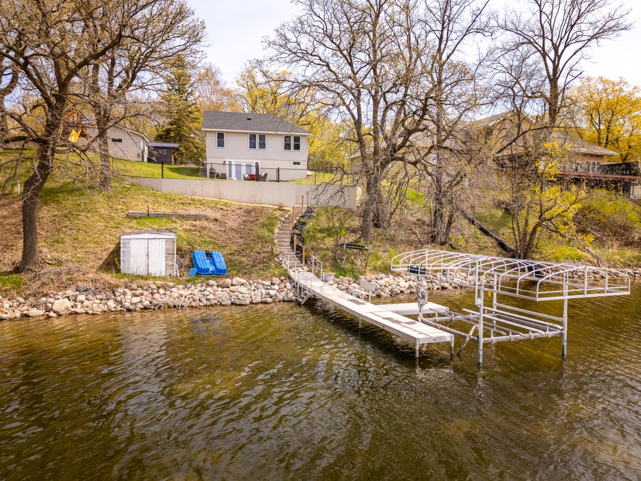 Aerial view from the lake, showcasing the back of the home along with the dock and lift.