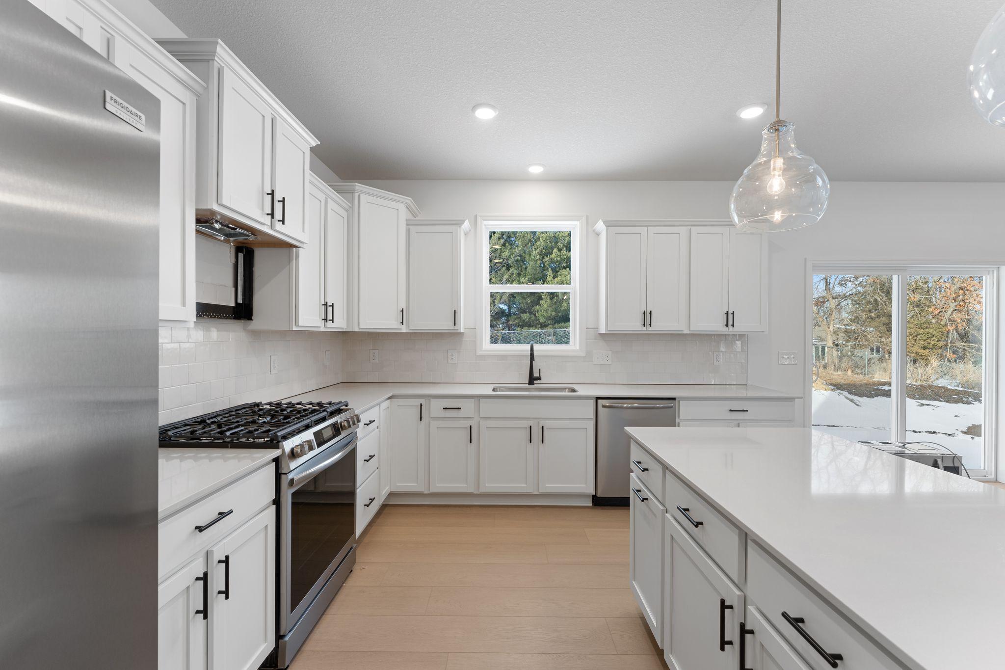 (Photo of a similar home, actual finishes may vary) This stylish and multifunctional kitchen comes complete with brand-new stainless steel appliances, sleek quartz countertops and Shaker-style cabinetry.