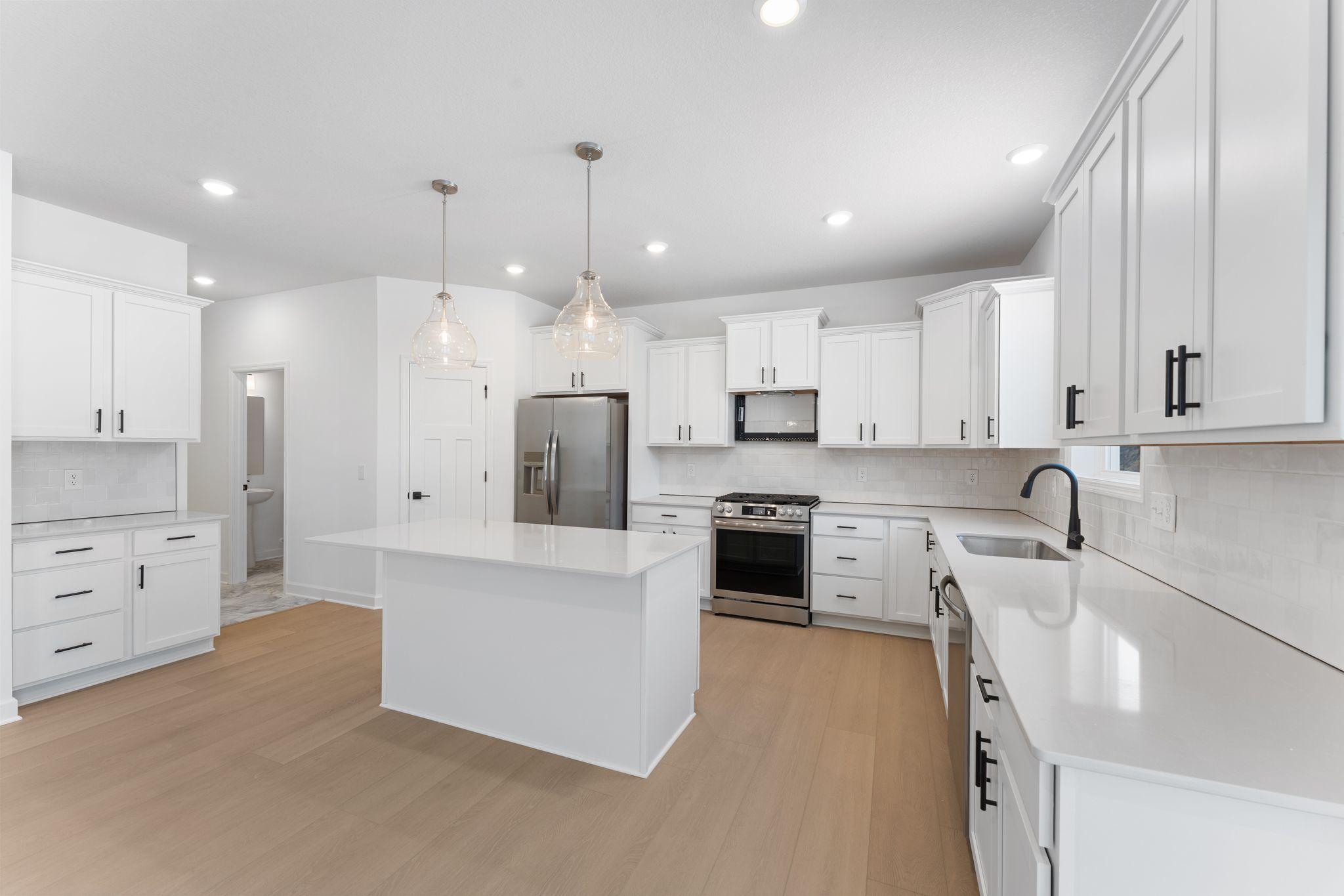 (Photo of a similar home, actual finishes may vary) The center island extends out to an overhang with space for bar-style seating