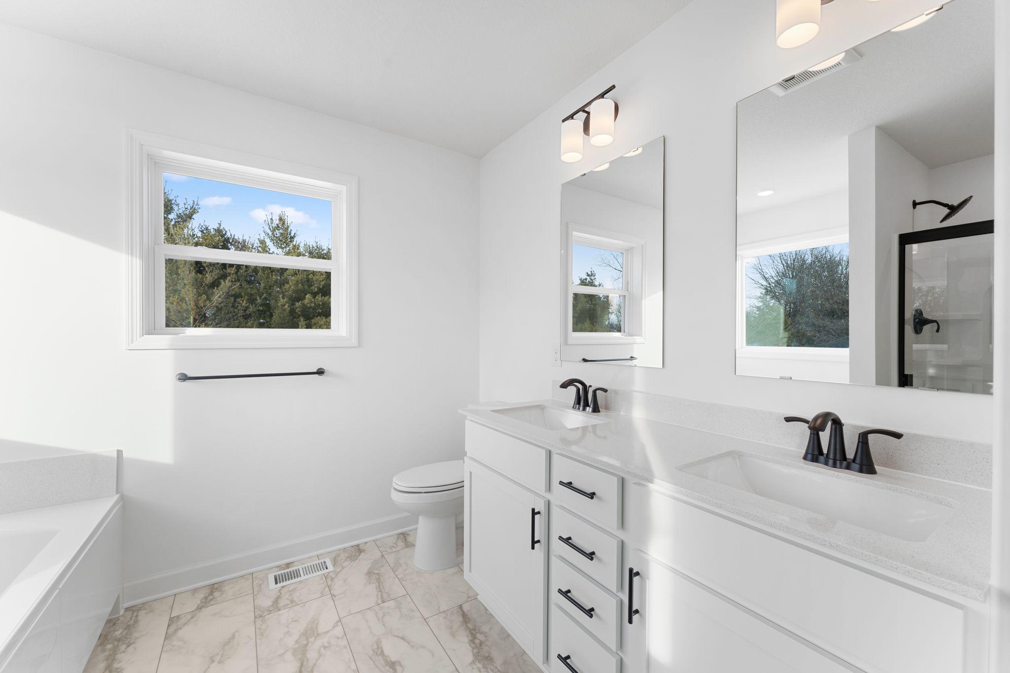 (Photo of a similar home, actual finishes may vary) A dual sinks, glass-enclosed shower, and separate soaking tub contribute to the bathroom’s spa-like atmosphere