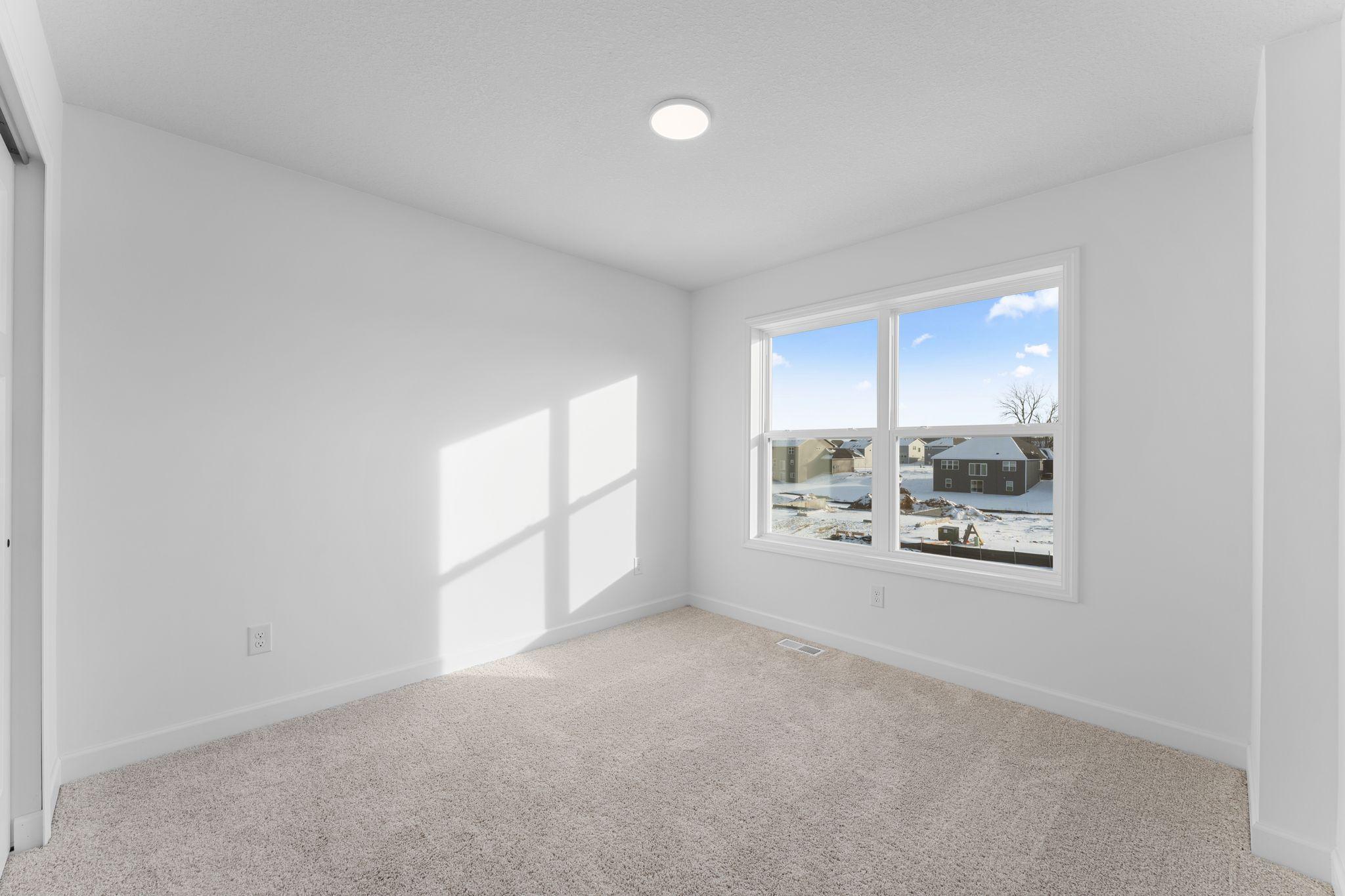 (Photo of a similar home, actual finishes may vary) All the secondary bedrooms include a practical wardrobe closet and wall-to-wall carpeting for plush comfort.