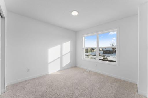 (Photo of a similar home, actual finishes may vary) All the secondary bedrooms include a practical wardrobe closet and wall-to-wall carpeting for plush comfort.
