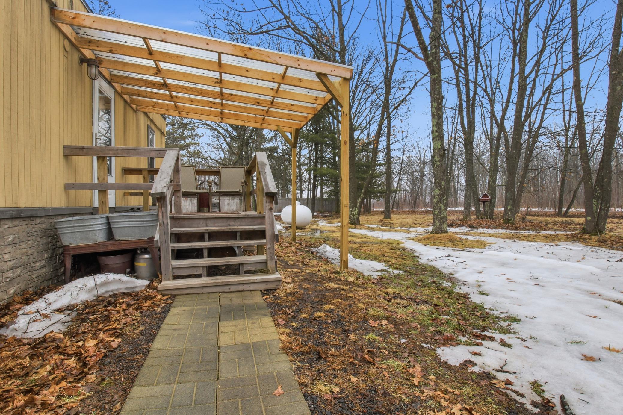 A welcoming covered entry with a pergola-style porch creates a cozy place to relax and enjoy the peaceful wooded setting in Onamia.