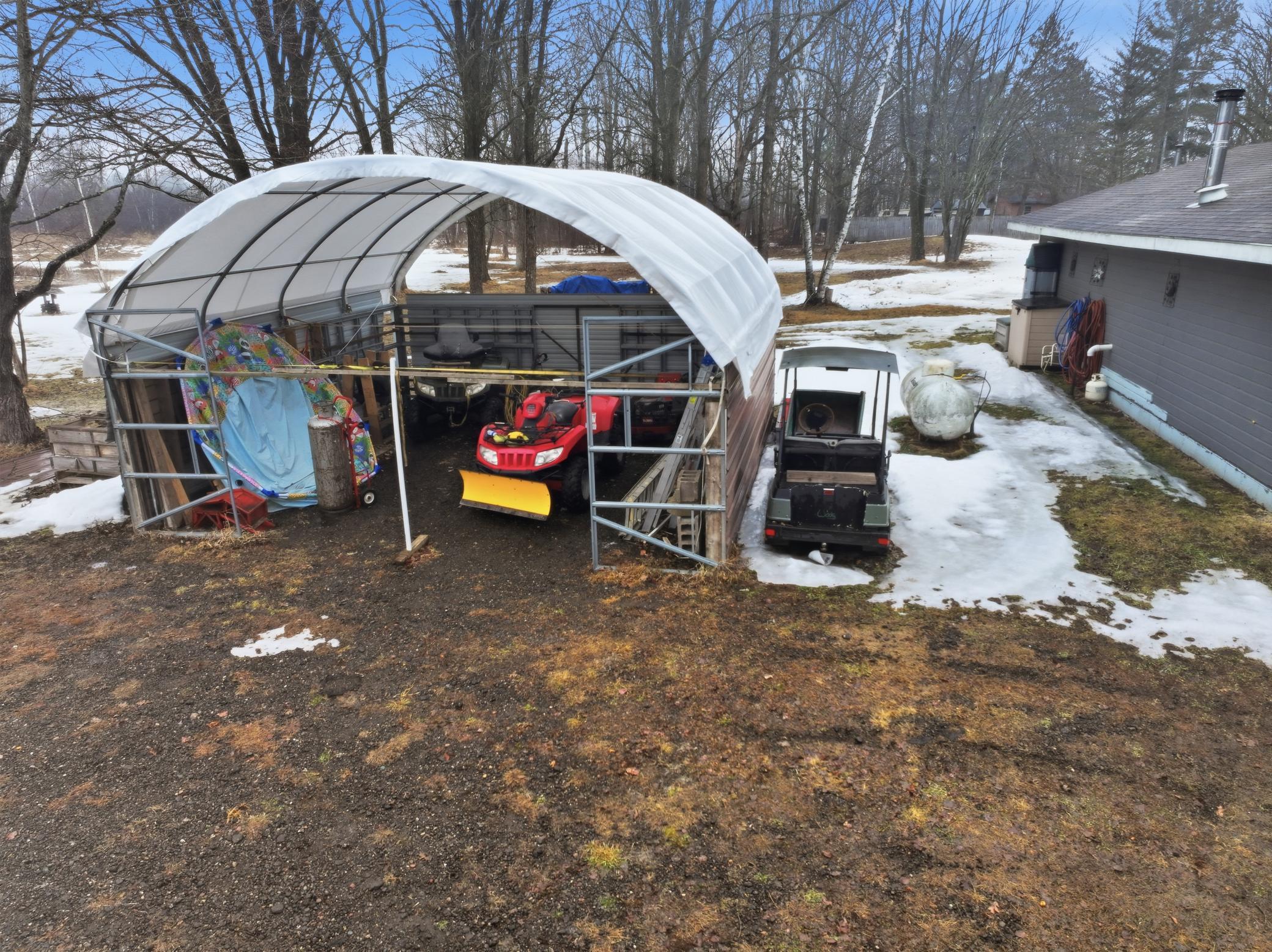 Covered storage area perfect for outdoor equipment, recreational vehicles, or additional workspace. (Seperate sale of interested)