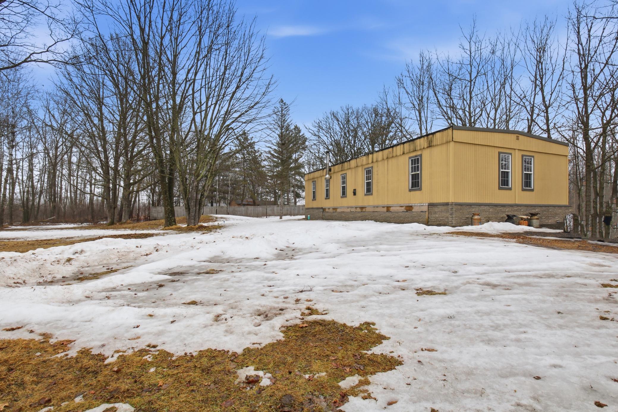 Side view of the home with open yard space and established trees surrounding the property.