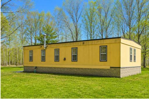 Side view of the home with open yard space and established trees surrounding the property.