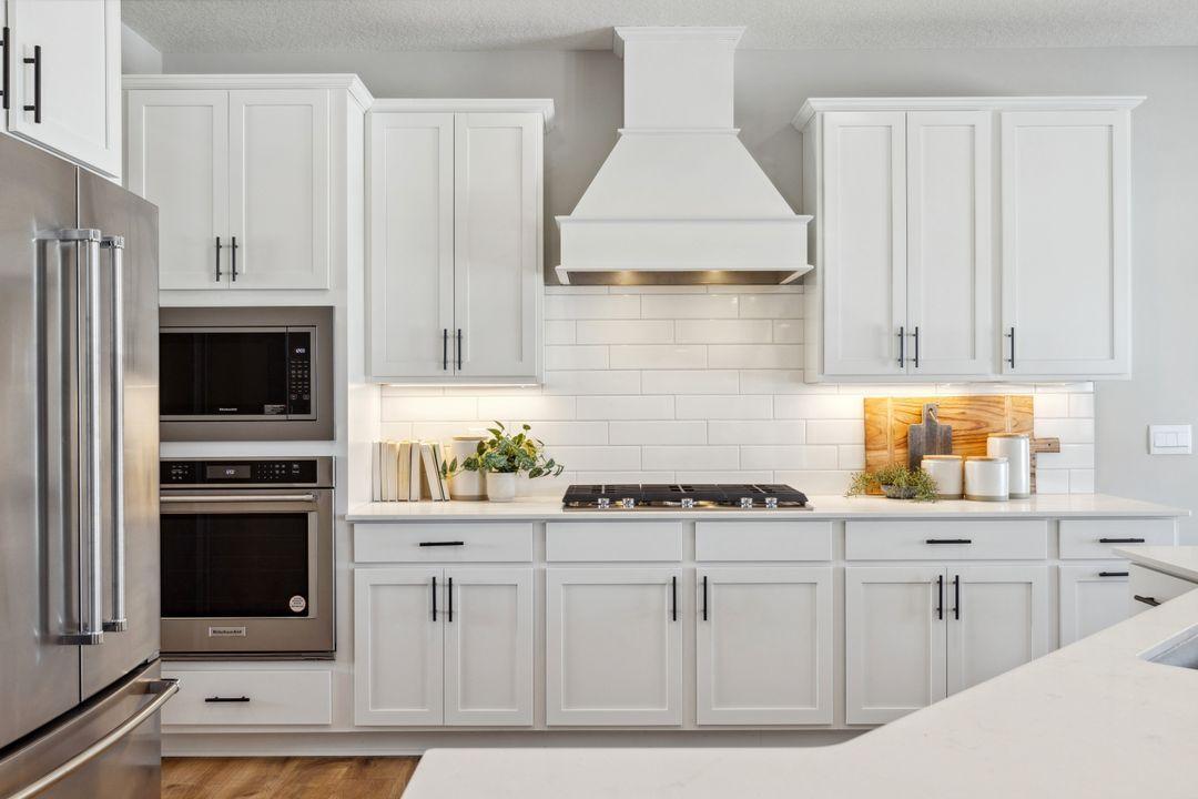 Stunning wood hood, gas cooktop, built in wall oven and microwave. Photo of a model home, color & options will vary.