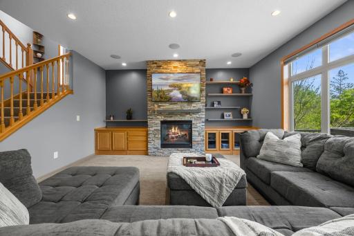 Just beyond, the welcoming family room showcases oversized windows that flood the space with sunlight and a stunning stone fireplace that serves as the focal point of the room.