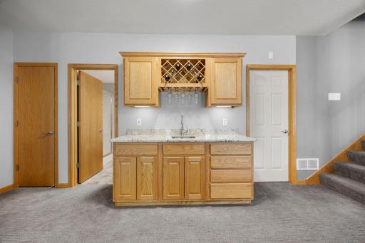 The wet bar, ideal for entertaining, offers ample counter and cabinetry space, along with a sink and wine rack.