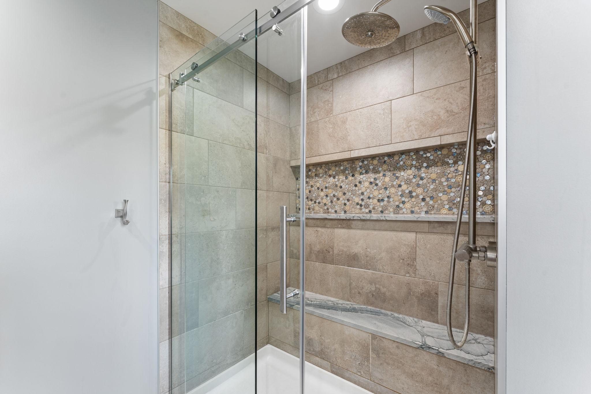The private primary bath features a walk-in tile shower with a built-in bench.