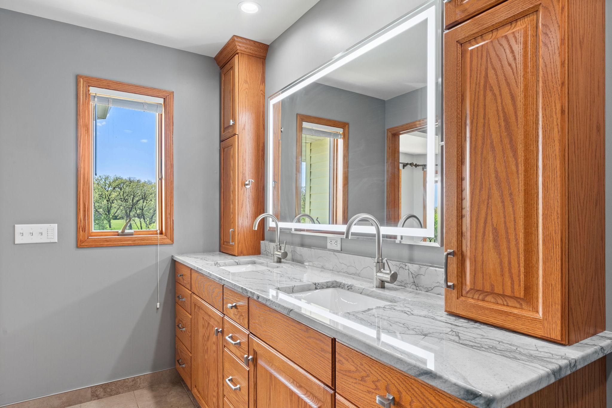 Featuring heated tile floors, linen storage, and a lighted vanity mirror.