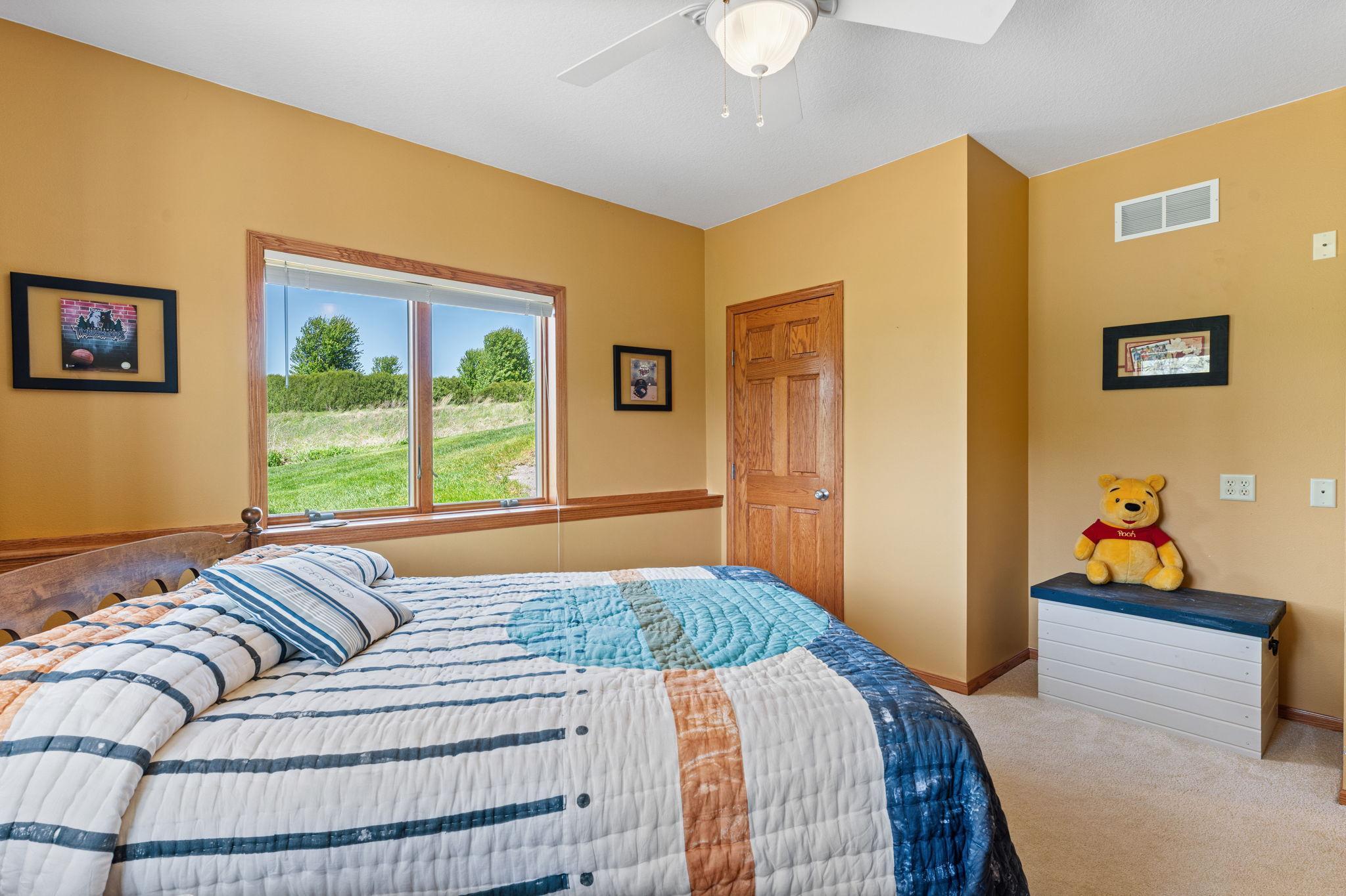 A lower-level fourth bedroom features a walk-in closet, natural light, and backyard pond views