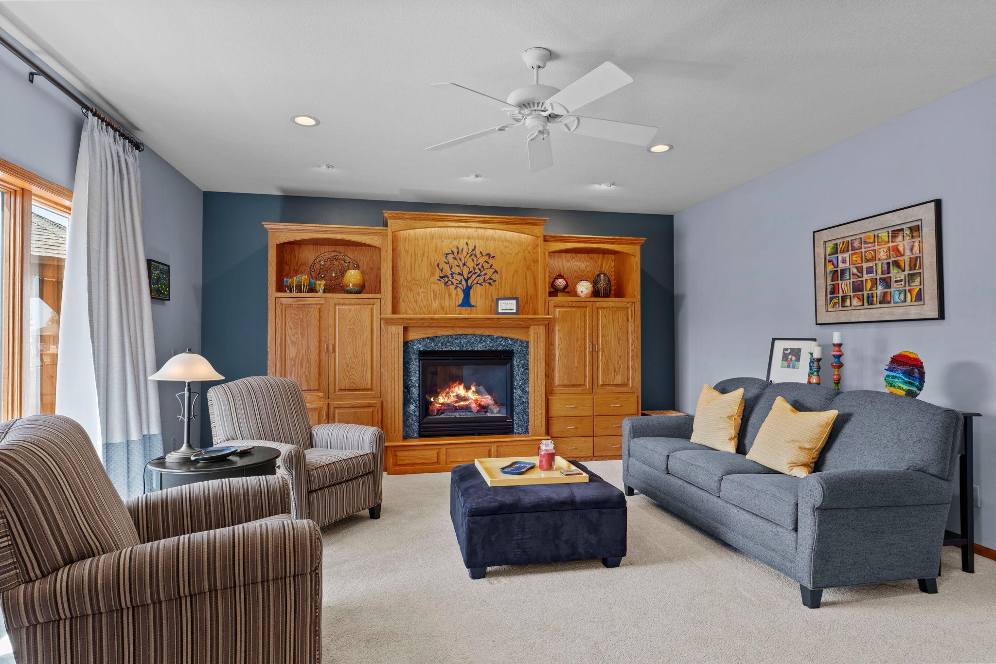 Beautiful fireplace surrounded by custom oak built-in cabinetry with accent lighting and generous storage.