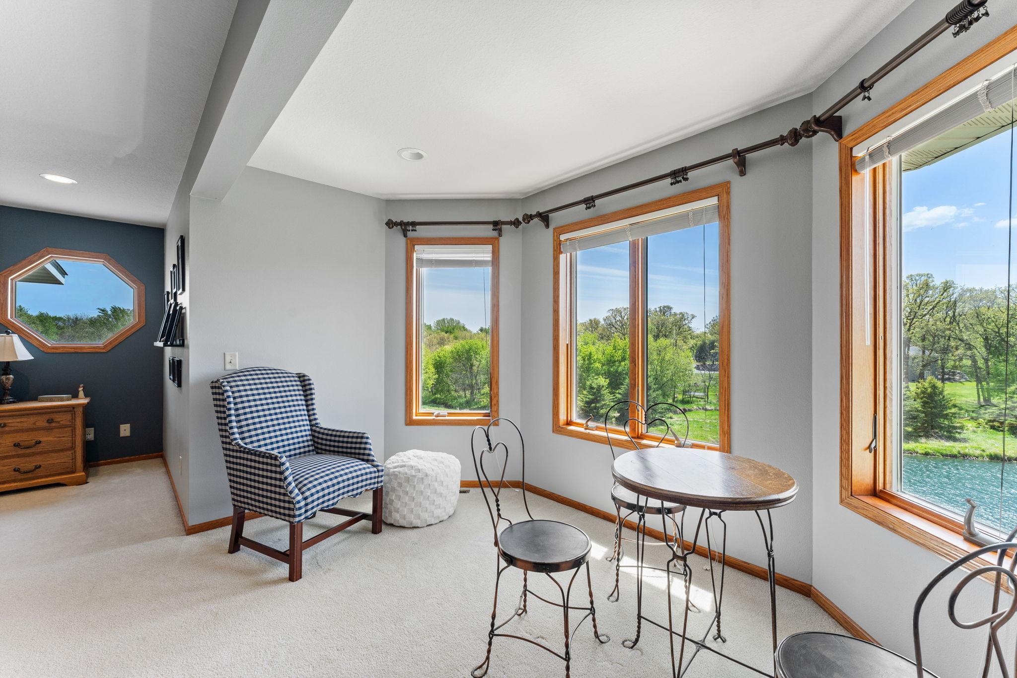 A charming bay alcove in the primary suite creates a second sitting area with serene views of the backyard, pond, and open prairie.