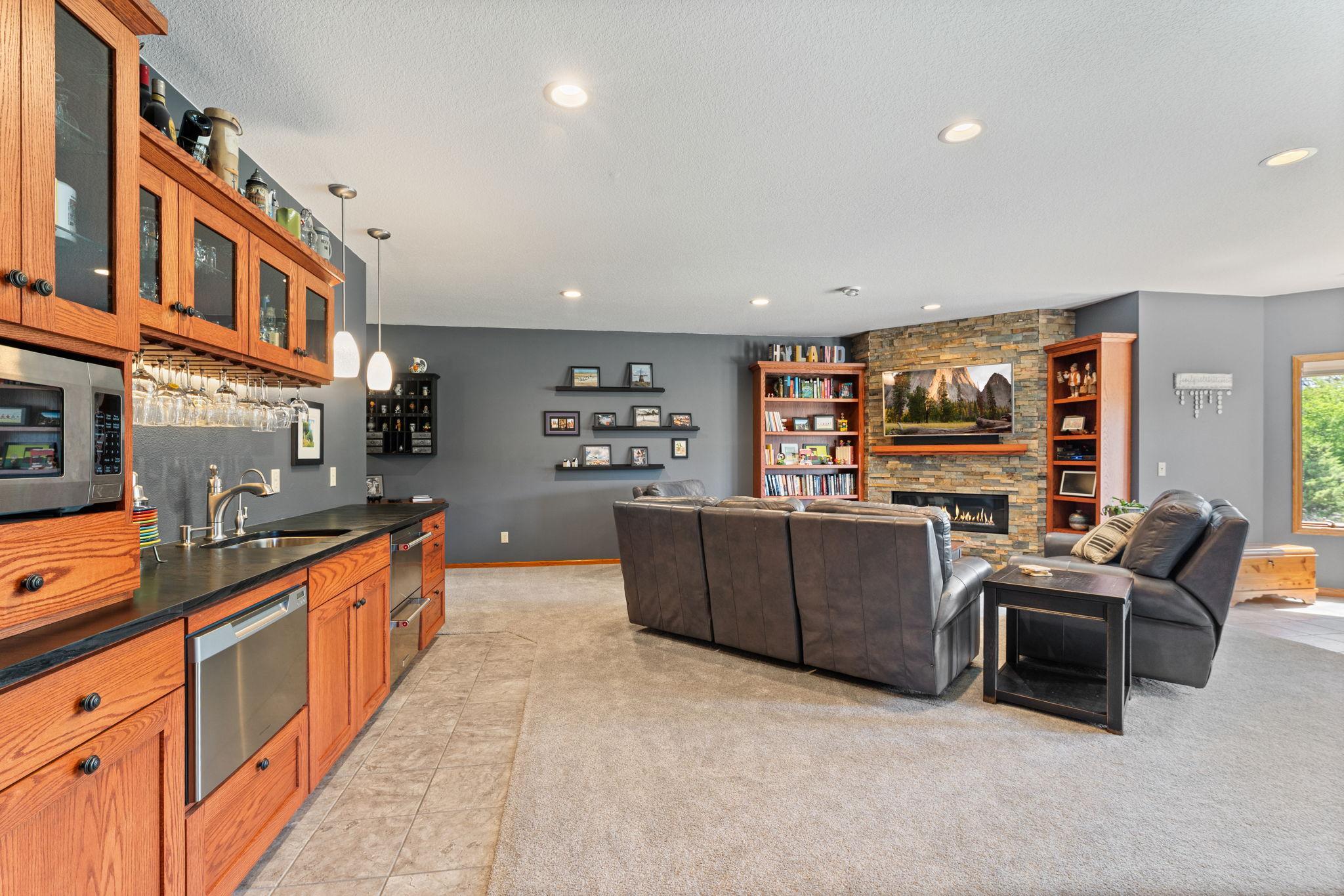 The lower-level family room is anchored by a stunning stone-surround fireplace with nearby bar.
