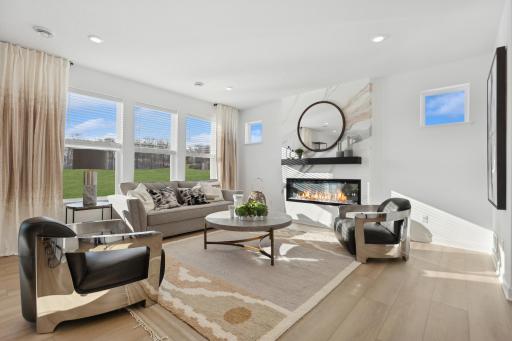 Photo is of the actual model. The spacious family gathering area seamlessly connects to the kitchen area, perfect for entertaining. It also features many large windows providing warm natural light and a fireplace.