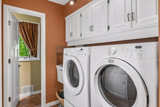 Main floor laundry w utility sink and cabinets.