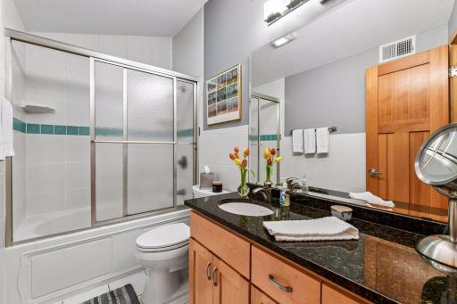 Upper level full bath w Kohler fixtures: jetted tub, tiled flooring and walls, granite counter and maple cabinets w storage and drawers.