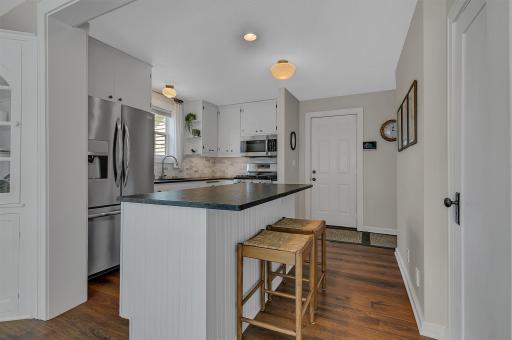 Updated kitchen featuring stainless steel appliances, a beadboard accent island with seating, and a handy rear entry door.