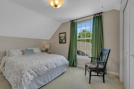 The charming third bedroom features a generous layout with plush carpeting, neutral walls, and large window brings in plenty of natural light and looks out over the property