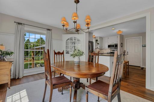 Alternate view of the dining area highlighting the open-concept layout to the kitchen, character-rich wall molding, and fantastic natural light.