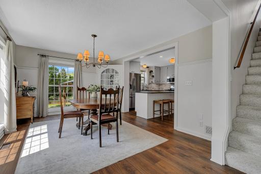 Beautiful dining room boasting new LVP floors, elegant character molding, a built-in corner cabinet, and seamless flow into the kitchen area.