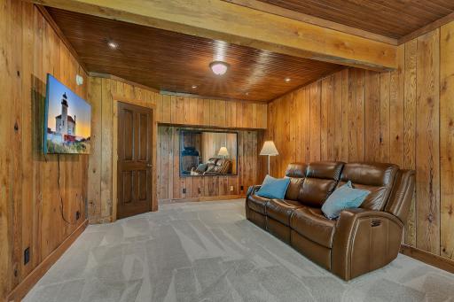 Inviting lower-level family room showcasing rustic wood planking, a tongue-and-groove wood ceiling, new carpeting, and a cozy layout for relaxation