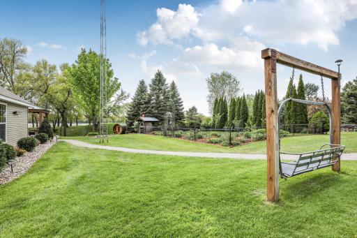 An outdoor paradise! The beautifully landscaped yard features lush gardens, a custom wood-fired pizza oven, and a relaxing barrel sauna for the ultimate backyard retreat. (Note: Wooden lawn swing is excluded from the sale.)