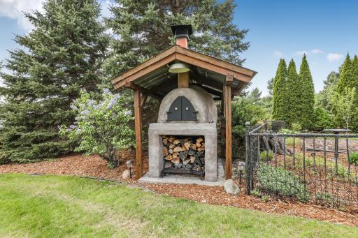 Cook gourmet meals outdoors with this impressive, custom stone pizza oven featuring its own protective roof and a handy log storage niche.
