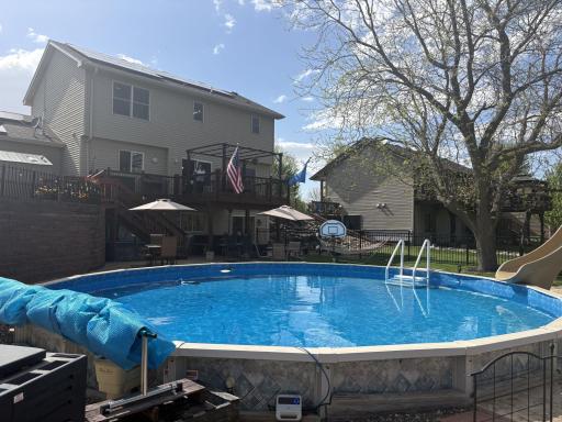 Step outside to your own resort-style retreat featuring an in-ground pool, waterfall feature, fire pit area, stamped concrete patio, and panoramic golf course views, an ideal setting for relaxing or entertaining.