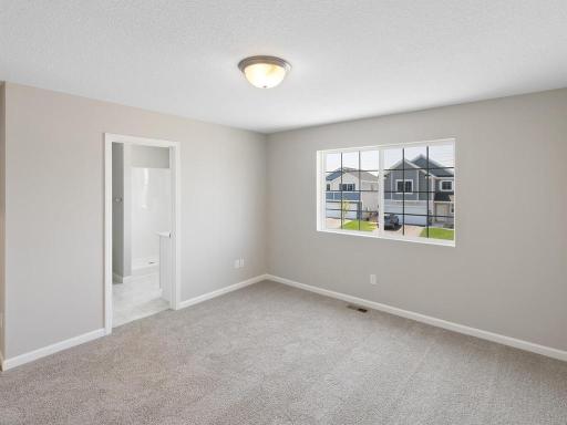Primary Suite. Photo taken of another home with similar plan and finishes. Photos and renderings may not depict actual plan, materials, & finishes may vary. All measurements are approximate.