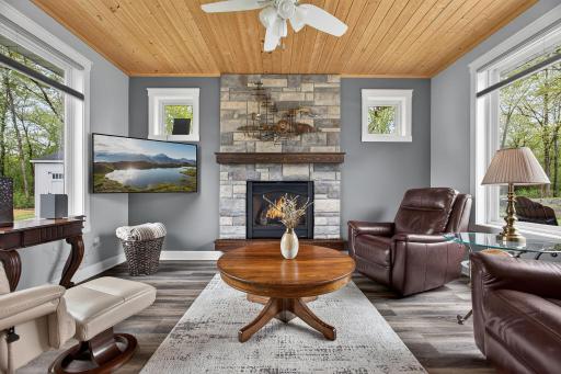 Four-season sunroom featuring a cozy gas fireplace, oversized windows, and a stunning stone surroundâperfect for year-round comfort and natural light.