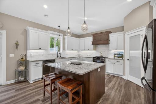 Well-appointed kitchen featuring a vented hood, granite countertops, and a custom tile backsplashâblending function with timeless style.