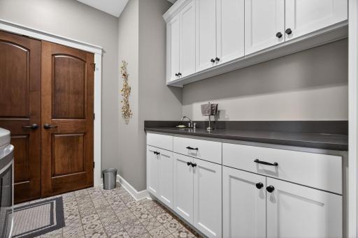Spacious laundry/mud room featuring ample countertop space, abundant cabinetry, a utility sink, and a large closetâdesigned for efficiency and everyday convenience.