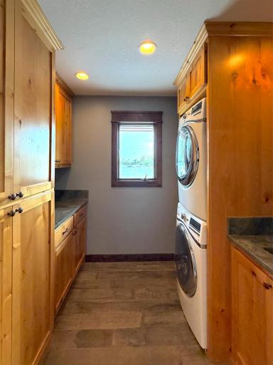 Charming laundry space with stacked washer/dryer, utility sink, and lots of storage in rich hickory cabinetry. House is forced air electric dual heat.