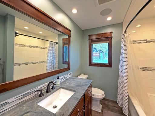 Full bathroom featuring elegant tile work in the tub/shower and large granite counters with tile backsplash.
