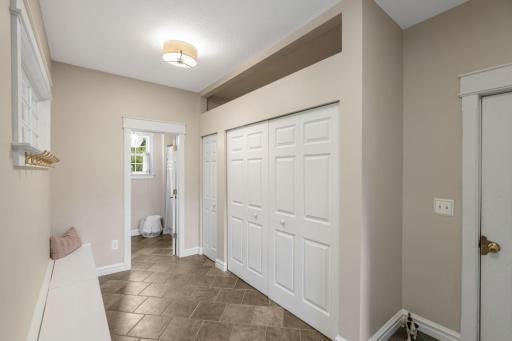 A spacious mudroom, accessible from the oversized 2-car attached garage, features tile floors, bench, hooks, and closet storage.