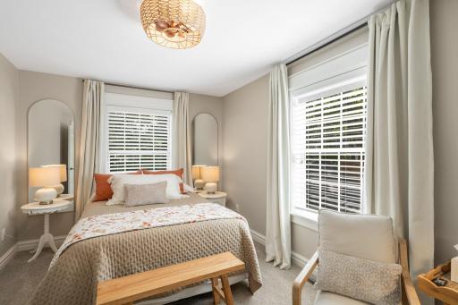 Bedroom two offers a comfortable, stylish space with two large windows and a unique ceiling fan with light fixture.